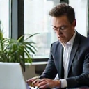 Hombre de negocios en su oficina, trabajando en una computadora portátil con una expresión serena y productiva.