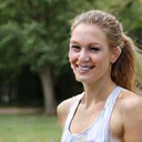 Mujer sonriendo y haciendo ejercicio al aire libre, con un aspecto saludable y feliz.